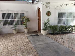 A house with a tiled patio, potted plants, a door, and barred windows. - Jaguar Condos Cozumel The Private Group Villa / Casa 1-24 w/2 pools Downtown (Cozumel)