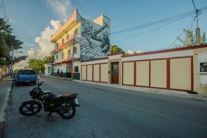 Eine Straße mit einem Wandgemälde an einem Gebäude, einem abgestellten Motorrad und einem Auto.