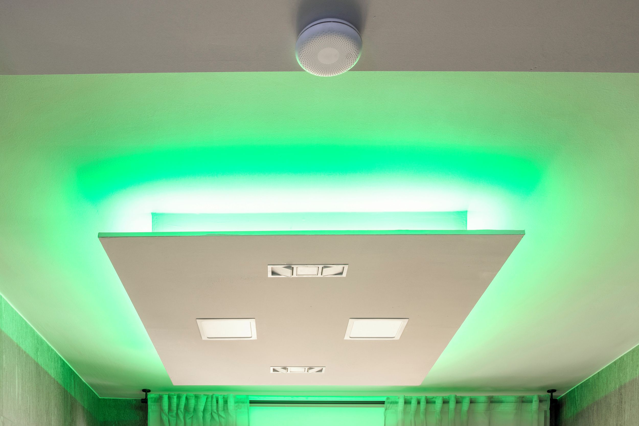 Un plafond doté d’un éclairage encastré et d’un détecteur de fumée.
