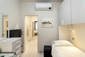 Une chambre d’hôtel équipée d’un lit, d’un bureau, d’une chaise, d’une armoire et d’un appareil de climatisation.