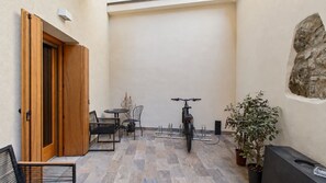 Un petit espace patio avec une table et des chaises, un vélo et une plante en pot.