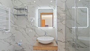 A bathroom with a marble wall, a wooden vanity, a white sink, and a glass shower enclosure. - Love Story - inclusa ricca colazione a buffet (Cormons)