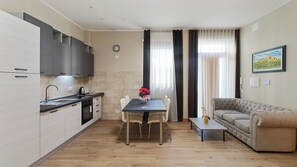 A modern kitchen with a dining area, a sofa, and a painting on the wall. - Love Story - inclusa ricca colazione a buffet (Cormons)