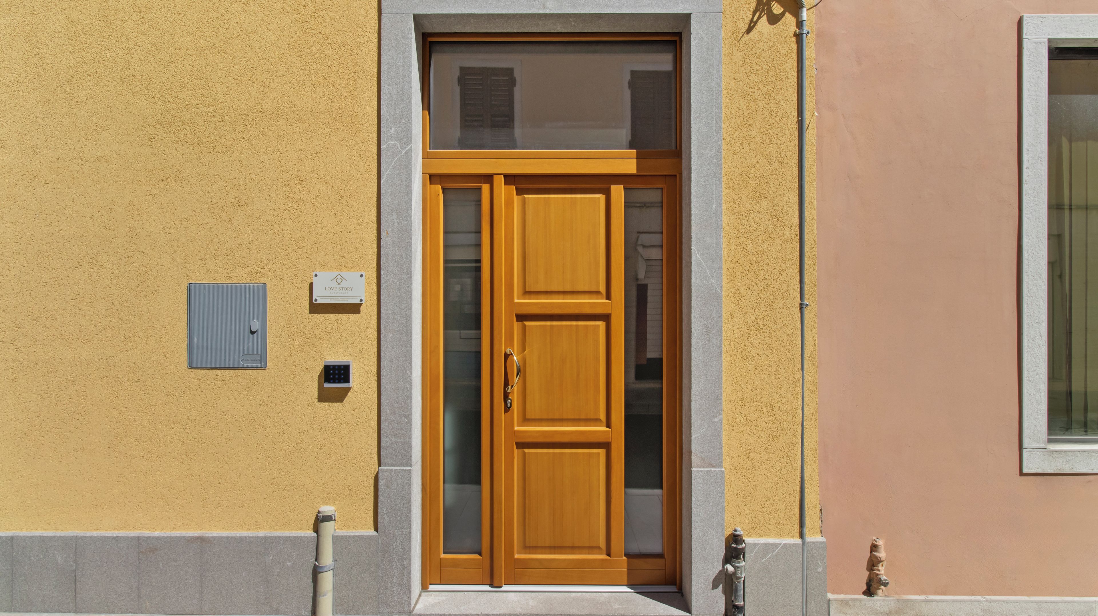 Una porta in legno con un pannello di vetro, una tastierina numerica e un cartello con la scritta 'LOVE STORY'.