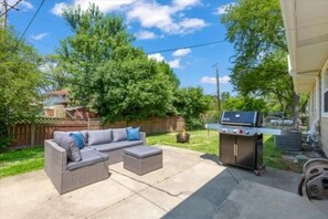 A backyard with a patio area, a grill, and a wooden fence. - Ample and inviting 4-bedroom 2-bathroom house in serene Des Plaines (Des Plaines)