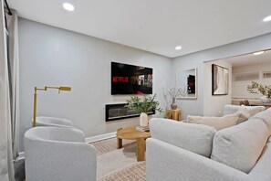 A modern living room with a flat-screen TV, a gold floor lamp, and a sofa set. - Ample and inviting 4-bedroom 2-bathroom house in serene Des Plaines (Des Plaines)