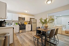 A modern kitchen with white cabinets, stainless steel appliances, and a dining area with a table and chairs. - Ample and inviting 4-bedroom 2-bathroom house in serene Des Plaines (Des Plaines)