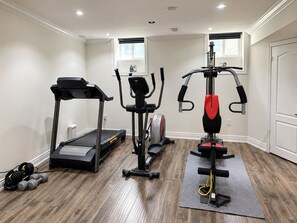 A home gym with a treadmill, elliptical, and weight machine. - Private Suite | Sauna, Cinema, Gym & Pool Table (King)
