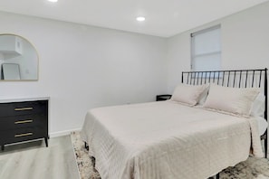 Une chambre à coucher avec un lit, une commode, un miroir et une fenêtre.