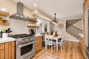 A modern kitchen with a stove, oven, and wooden cabinets. - Treehouse on Daly | Steps to Main St & Trolley (Park City)