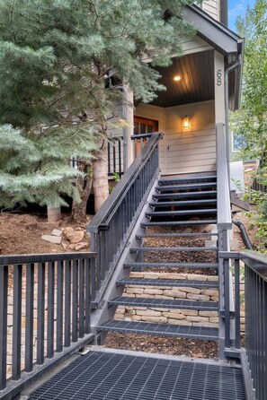 A wooden staircase with a metal railing leading to a house entrance. - Treehouse on Daly | Steps to Main St & Trolley (Park City)