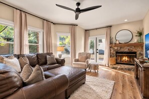 A living room with a fireplace, leather sofas, and a ceiling fan. - Treehouse on Daly | Steps to Main St & Trolley (Park City)