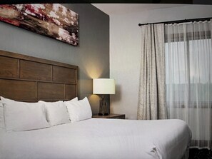 A hotel room with a large bed, a headboard, a bedside lamp, a window with sheer curtains, and a painting on the wall. - Wyndham Glacier Canyon at the Wilderness Wisconsin Dells Waterpark. 3 br Condo (Baraboo)