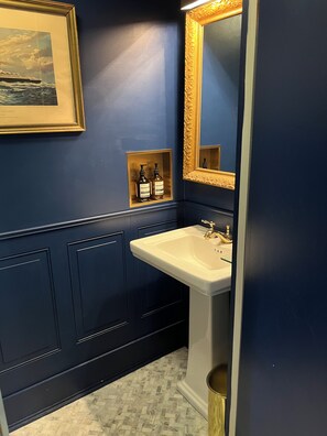 A bathroom with a white sink, a gold-framed mirror, and a framed picture on the wall. - 1781 Country Estate • 55 Private Acres • Inn-Style Hospitality (Greenwich)