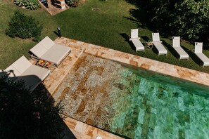 Eine Vogelperspektive auf einen Poolbereich mit Liegestühlen und einem Grill.