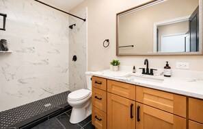Ein modernes Badezimmer mit Dusche, Toilette, Waschtisch und einem großen Spiegel.