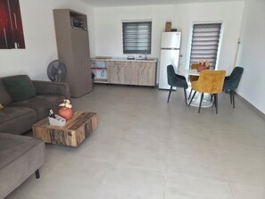Ein Wohnzimmer mit Sofa, Couchtisch und einem Essbereich mit Stühlen und Tisch.