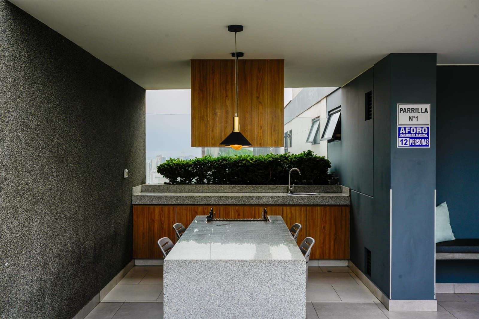 A modern kitchen with a granite countertop, wooden cabinets, a built-in sink, and a pendant light.