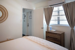 A bedroom with a bed, a dresser, a mirror, and a window with curtains. - Tide · Beach days, family nights (Cocoa Beach)