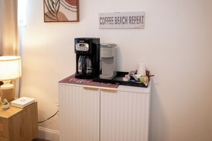 Eine Küchenzeile mit Kaffeemaschine, Wasserspender und einer Kaffeetasse auf der Arbeitsfläche.