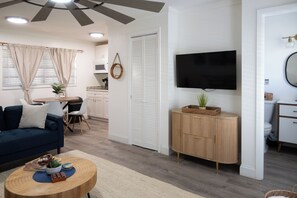 Ein modernes Wohnzimmer mit einer Couch, einem Couchtisch und einem an der Wand befestigten Fernseher.