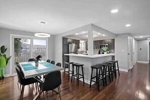 A modern kitchen with a central island, bar stools, and a dining area with a table and chairs. - Stylish and spacious 4-bedroom 2.5-bathroom home in Schaumburg (Schaumburg)