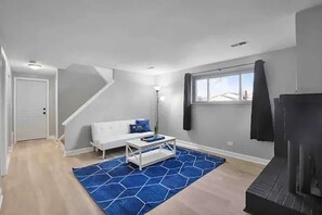 Ein modernes Wohnzimmer mit einem weißen Sofa, einem Couchtisch und einem blauen Teppich.