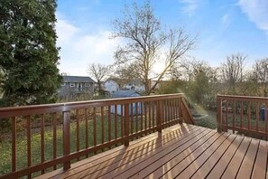 A wooden deck with a railing, surrounded by trees and a house in the background. - Stylish and spacious 4-bedroom 2.5-bathroom home in Schaumburg (Schaumburg)