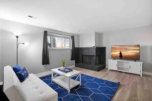 Ein modernes Wohnzimmer mit einer Couch, einem Couchtisch, einem Kamin und einem Fernseher.