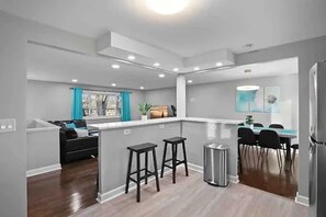 A modern kitchen with a central island, bar stools, and a dining area with chairs. - Stylish and spacious 4-bedroom 2.5-bathroom home in Schaumburg (Schaumburg)
