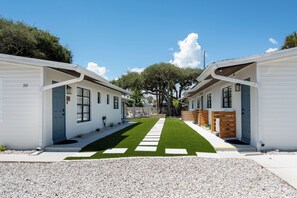 A row of white mobile homes with a central pathway. - Sand · Pack light, stay awhile | 2BR + laundry (Cocoa Beach)