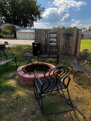 A fire pit area with seating, a wooden fence, and a sign welcoming visitors to the fire pit.