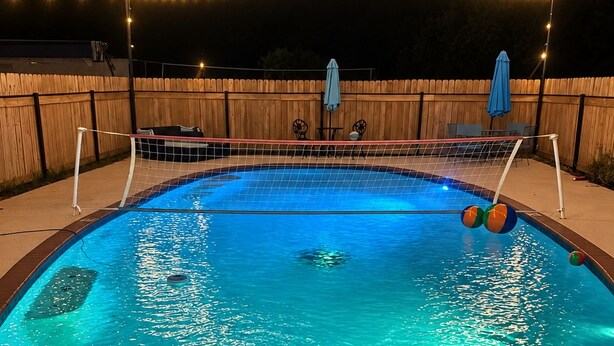 Una piscina con indicatore di profondità di 1,2 metri, circondata da una recinzione in legno e luci decorative a sospensione.
