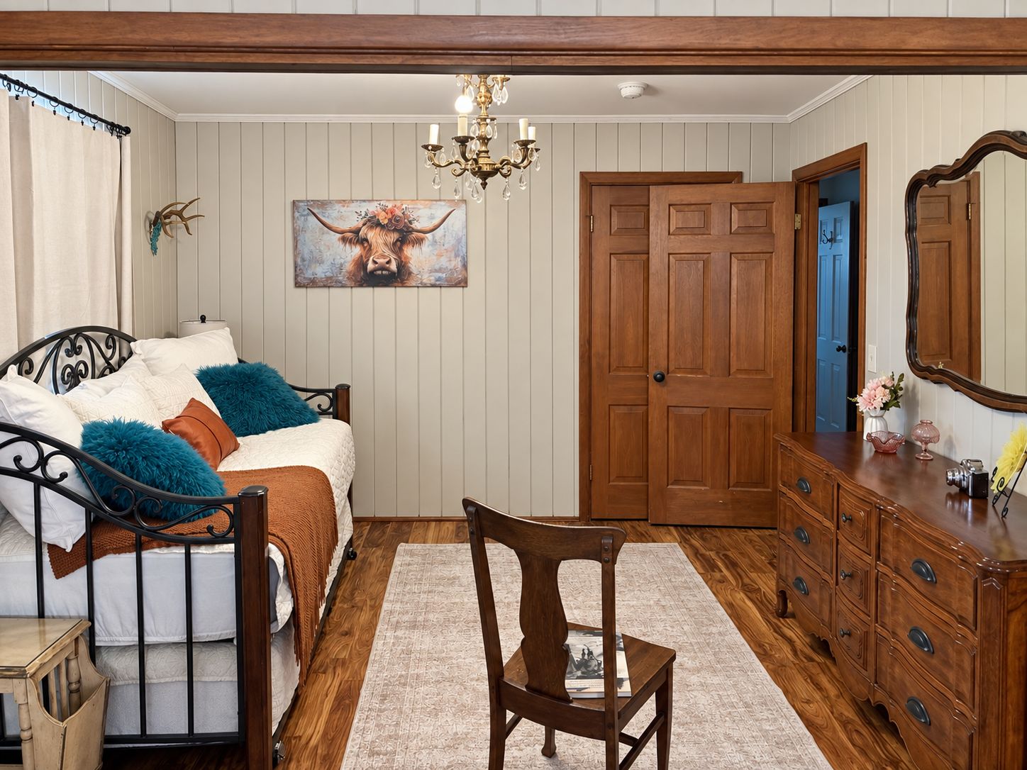 A bedroom with a bed, a dresser, a chair, a door, and a painting on the wall.