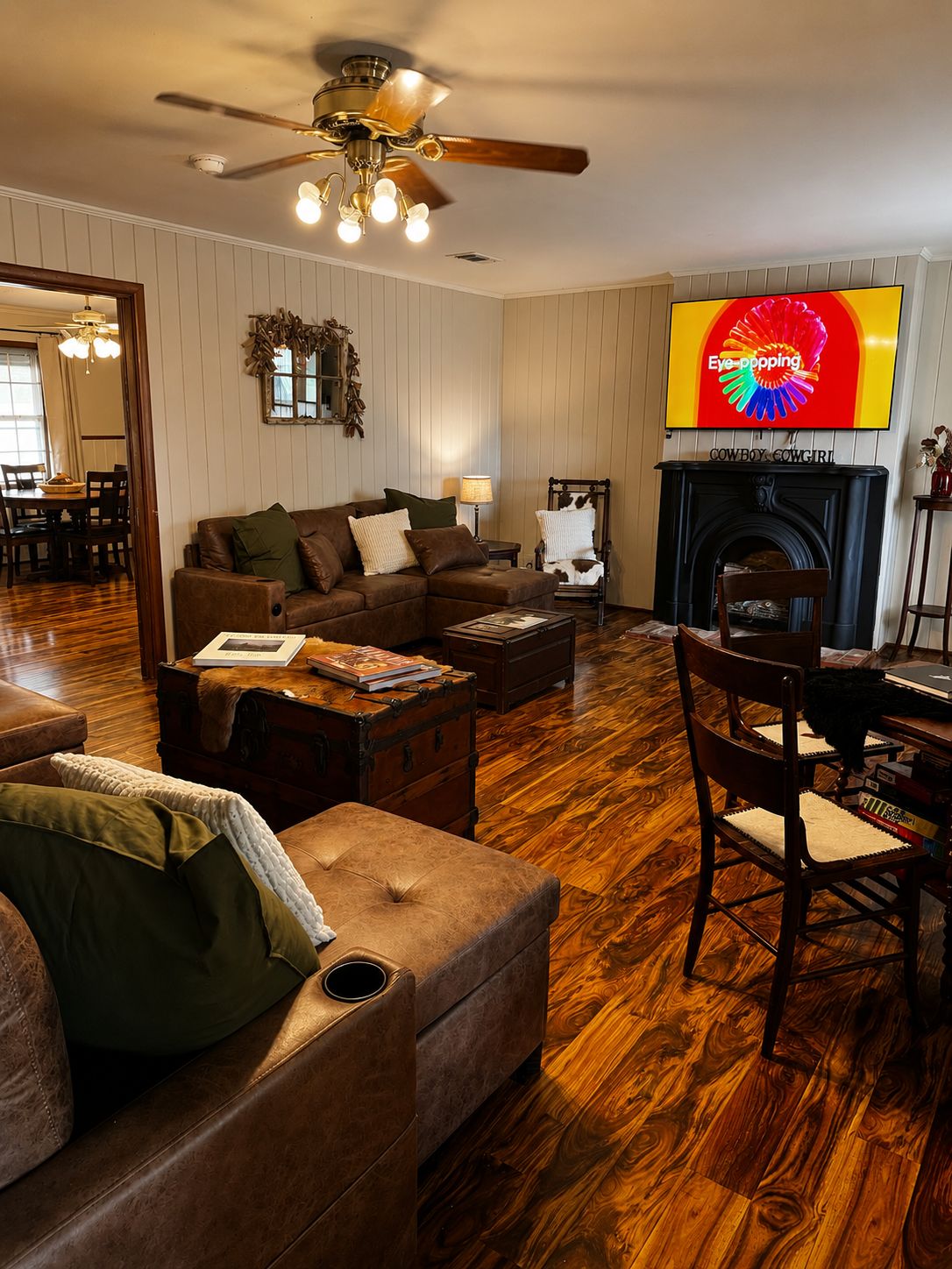 Una sala de estar con chimenea, ventilador de techo y televisor de pantalla plana montado encima.