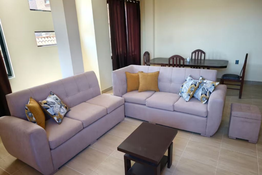 A living room with a sofa, a coffee table, and a dining table with chairs.