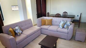 A living room with a sofa, a coffee table, and a dining table with chairs.