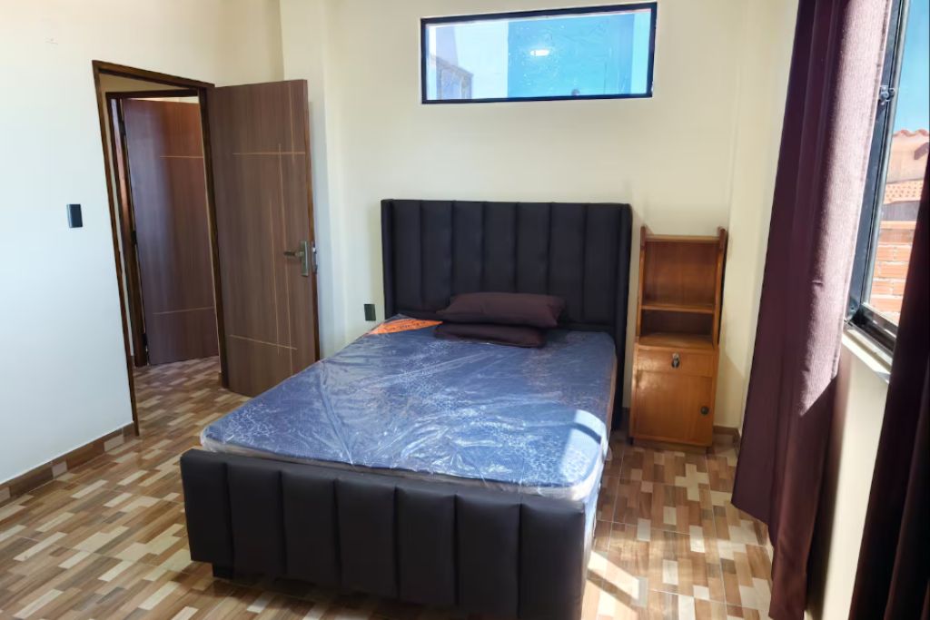 Une chambre à coucher avec un lit, une armoire, une table de chevet et une fenêtre.