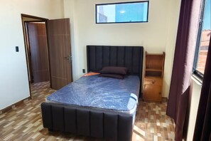 A bedroom with a bed, a wardrobe, a nightstand, and a window.