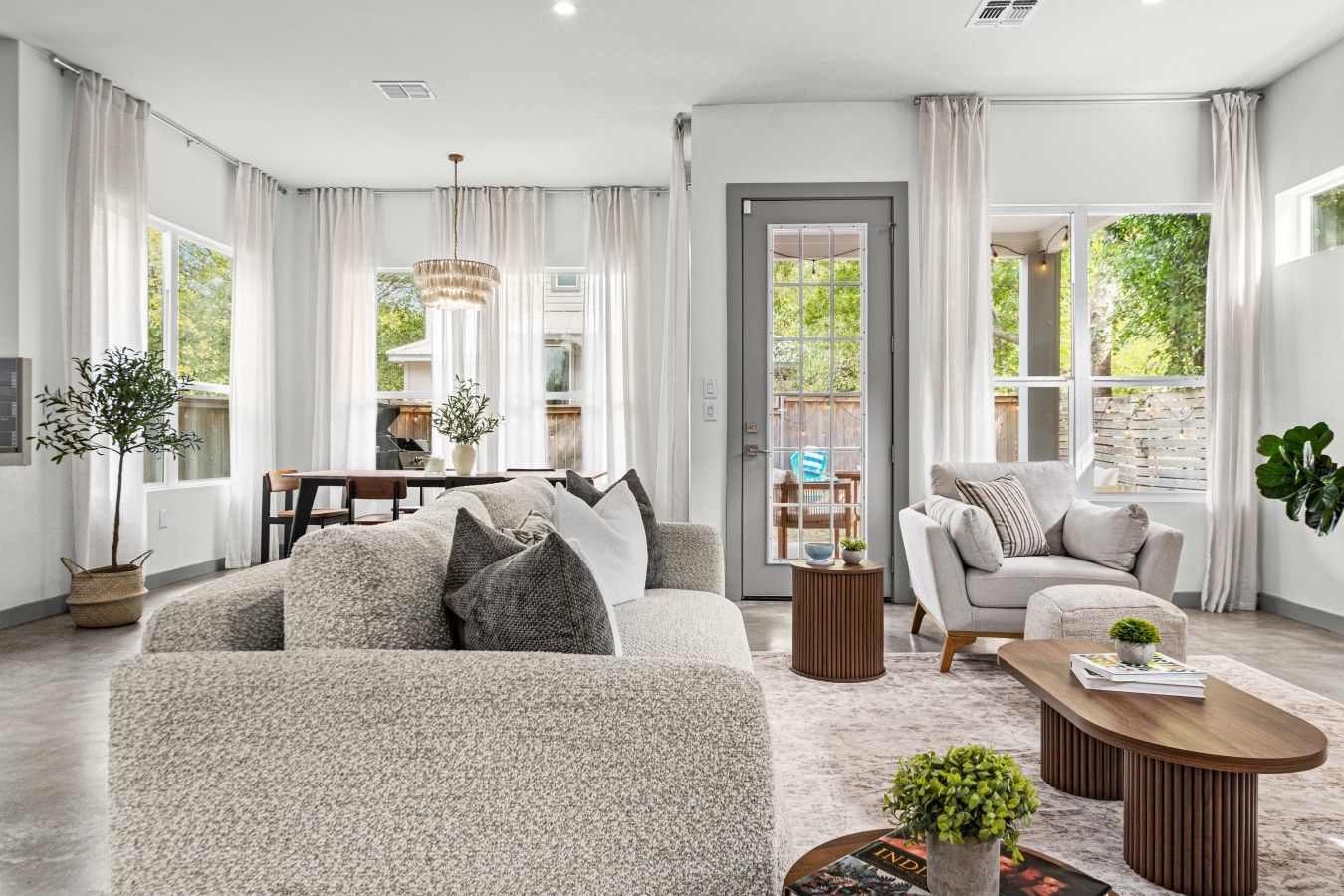 A spacious living room with a large sofa, a coffee table, and a dining area with a table and chairs.