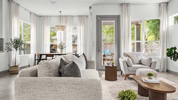 A spacious living room with a large sofa, a coffee table, and a dining area with a table and chairs.