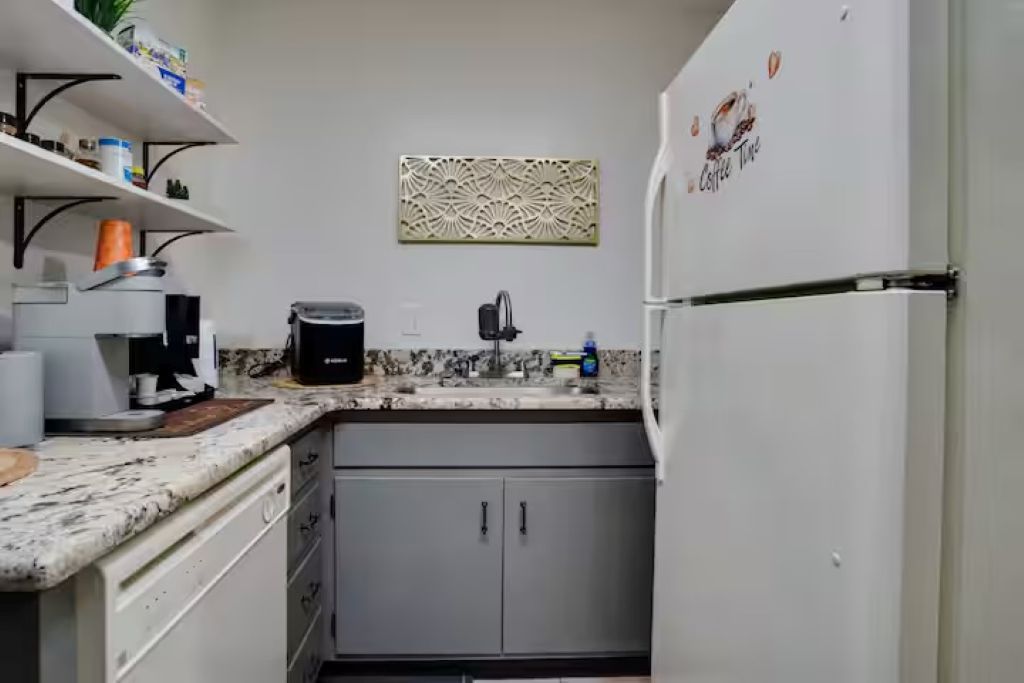 Cozinha compacta com cafeteira embutida, pia e geladeira.
