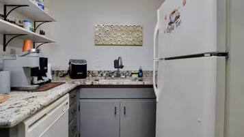 Cozinha compacta com cafeteira embutida, pia e geladeira.