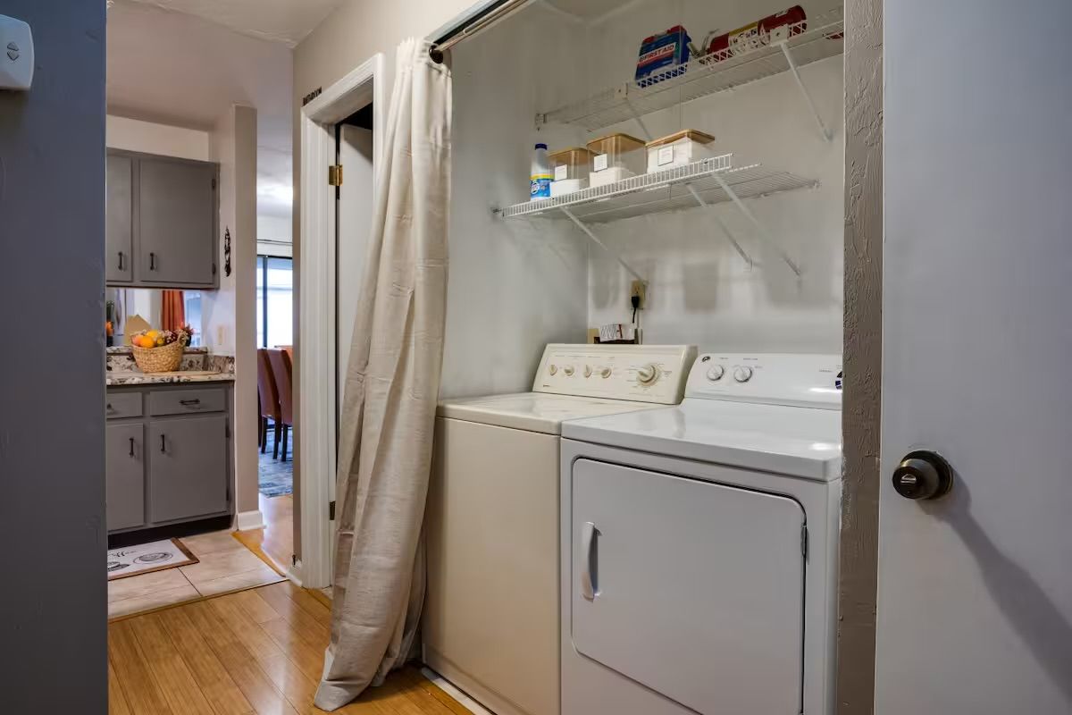 Un cuarto de lavado con lavadora, secadora y estantes con cajas de almacenamiento.