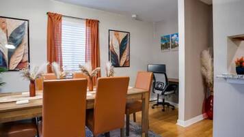 Uma sala de jantar com mesa de madeira, cadeiras laranjas e tapete azul.