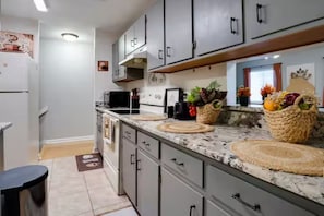 A kitchen with grey cabinets, a marble countertop, and woven placemats.