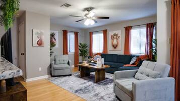 A living room with a ceiling fan, a grey sofa, a coffee table, and a grey armchair.