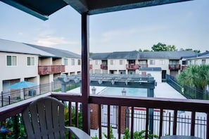 A covered outdoor area with a pool, a chair, and a view of residential buildings.