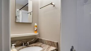 Ein Badezimmer mit Marmorwaschtisch, Spiegel, Handtuchhalter und einer Lotionflasche.