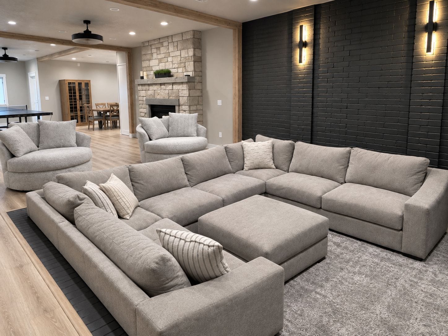 Un salon moderne avec un canapé d’angle, une cheminée et un mur d’accent en briques sombres.